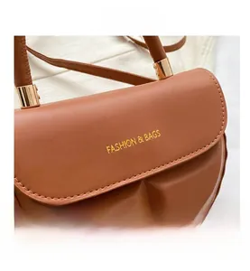 Close-up of brown leather crossbody bag with golden hardware and fashion lettering