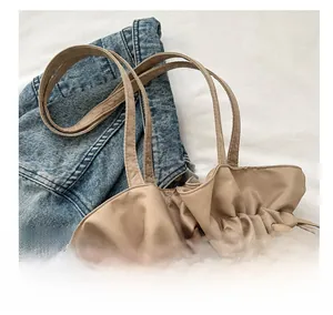 Detailaufnahme der khakifarbenen Kordelzug-Beuteltasche mit Plissee auf Jeans