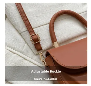Detail of adjustable gold buckle and lobster clasp on brown leather shoulder bag strap