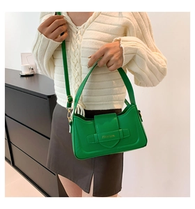 Detail of green leather underarm bag with gold logo and elegant buckle design