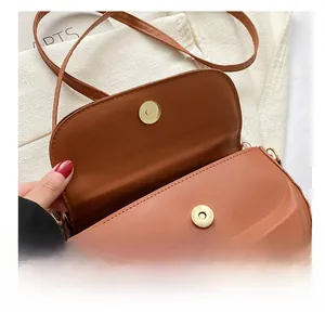 Detail of golden magnetic clasp and smooth brown leather texture on a saddle bag