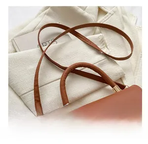 Close-up of caramel brown semi-circle bag with golden hardware and adjustable strap