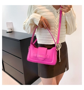Detail of bright pink leather shoulder bag featuring decorative buckle and gold logo