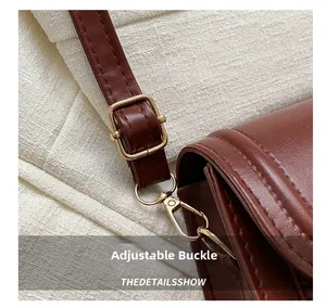 Détail de la bandoulière en cuir marron avec boucle en métal doré et mousqueton