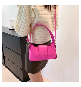 Detail view of a magenta baguette shoulder bag with gold hardware on a model