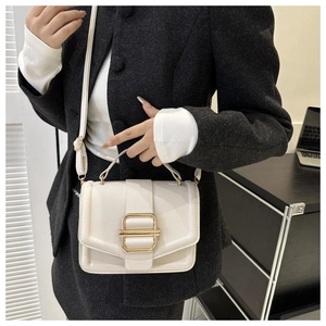 Close-up of white lychee leather handbag with a prominent gold square buckle and strap