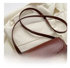 Détail de la bandoulière réglable et des boucles dorées sur le sac en cuir marron