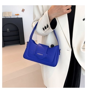 Detail of dark blue leather underarm bag with decorative buckle and embossed brand lettering