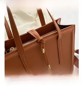 Gros plan d'un sac cabas en cuir marron montrant la fermeture éclair dorée et coutures
