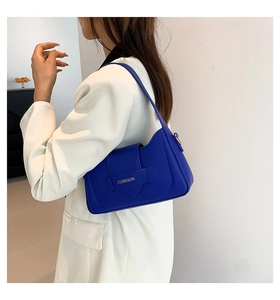 Detail of royal blue PU leather underarm bag with brand logo buckle and shoulder strap