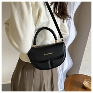 Detail of black semi-circular saddle bag featuring matte leather and gold metal hardware