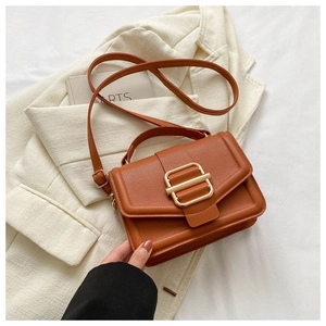Detail of caramel brown litchi grain faux leather crossbody bag with golden metal buckle