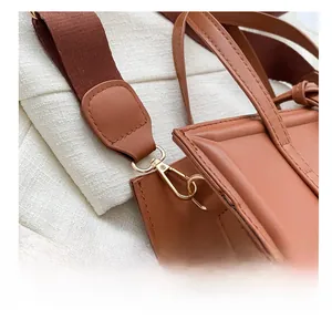 Gros plan du crochet doré et des coutures détaillées sur la bandoulière du sac marron