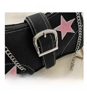 Detail of black canvas shoulder bag featuring pink star embroidery and silver metal chain