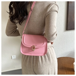 Détail d'un sac bandoulière rose sur un modèle montrant la taille et le fermoir doré