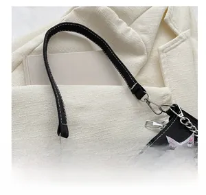 Detail of black canvas shoulder bag featuring pink star embroidery and silver buckle clasp