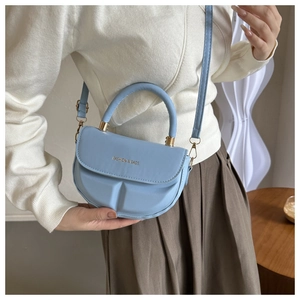 Close-up of light blue saddle bag with modular pleats and golden metal buckle details