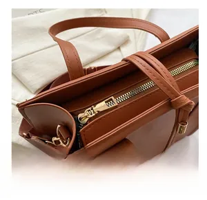 Détail du sac en similicuir marron avec fermeture éclair dorée et cordons déco