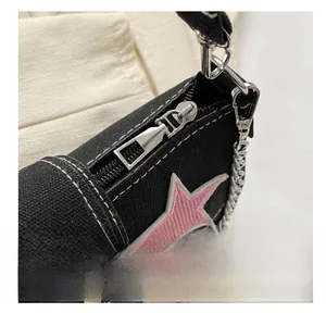 Detail of black canvas bag featuring pink star embroidery and silver chain strap