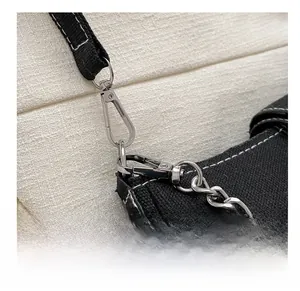 Detail of silver metal hooks and D-ring with black canvas strap on a retro shoulder bag