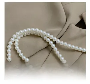 Détail de la bandoulière élégante en perles blanches doubles sur un sac en peluche