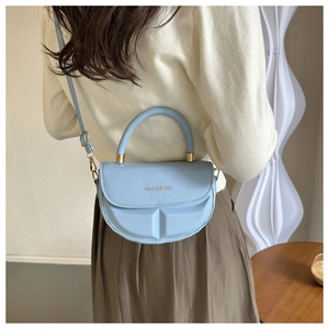 Detail of light blue semi-circular crossbody bag with geometric texture on back model