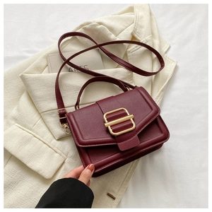 Detailed close-up of wine red lychee pattern leather bag with golden metal buckle