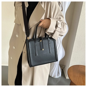 Détail du sac cabas en cuir noir minimaliste avec coutures verticales et pompons