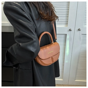 Brown semi-circular saddle bag with top handle and gold hardware on a model back view
