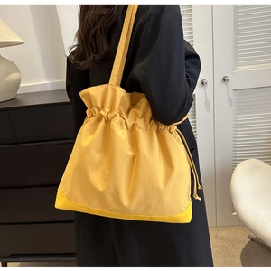 Detail einer gelben Beuteltasche mit Kordelzug, weichen Falten und verstärktem Boden