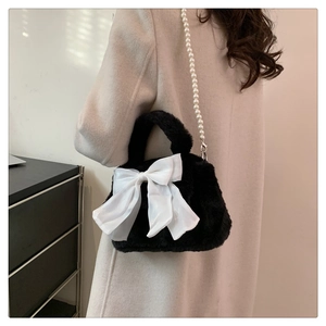 Dettaglio della borsa nera in peluche con grande fiocco bianco e tracolla di perle