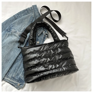 Detail of black quilted puffer tote bag with adjustable shoulder strap and carrying handle
