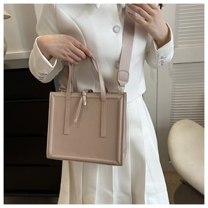 Détail d'un sac cabas en cuir kaki clair avec sangles verticales et bandoulière large