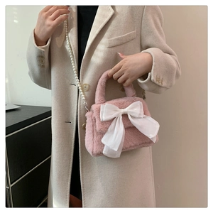 Détail du sac bandoulière en peluche rose avec grand nœud blanc et bandoulière perle