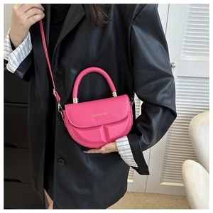Detailed close-up of a magenta faux leather saddle bag with gold logo lettering