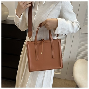 Détail d'un sac cabas carré marron avec bandoulière large et frange décorative fine