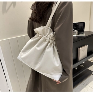 Detailansicht der weißen Bucket Bag aus Leder mit Kordelzug und Umhängeriemen im Alltag