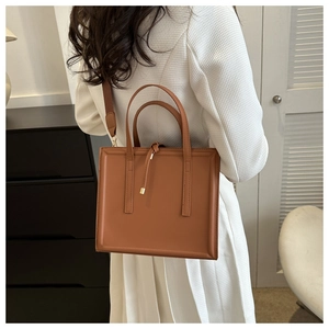 Sac fourre-tout marron porté par un mannequin dans un intérieur minimaliste