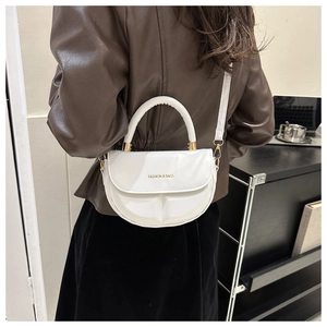 Close-up of a white saddle bag with golden hardware and fashion lettering detail