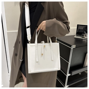 Gros plan d'un sac cabas en cuir blanc avec détails en métal doré et bandoulière large