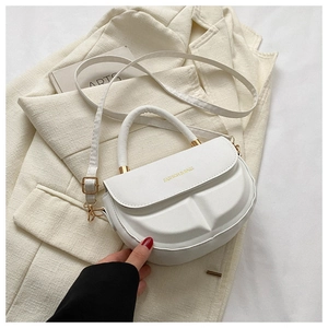 Detail of white PU leather saddle bag with gold metal hardware and fashion text