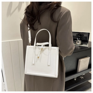 Détail d'un cabas blanc minimaliste avec sangles décoratives et large bandoulière en textile