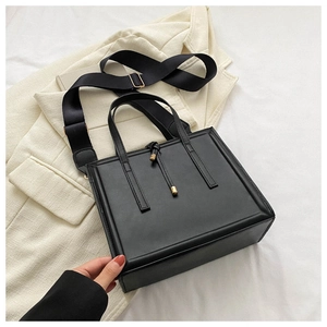 Détail du sac cabas noir mat avec ferrures dorées et bandoulière en tissu