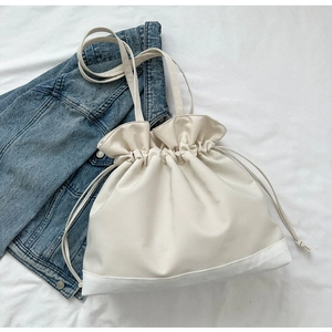 Detail der Kordelzug-Schultertasche mit Texturen aus weißem Leder und Canvas-Stoffmaterial