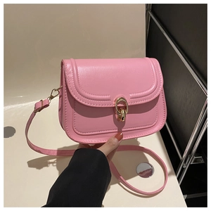 Détail d'un sac bandoulière rose en cuir avec une boucle métallique dorée élégante