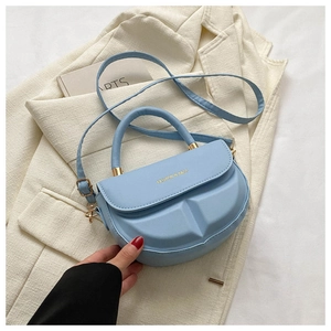 Detail of light blue saddle bag featuring 3D geometric embossing and gold lettering