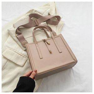 Vue détaillée du sac cabas beige avec large bandoulière et détails dorés sur un blazer