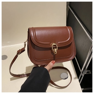 Détail du sac bandoulière marron caramel montrant le fermoir doré et le grain du cuir