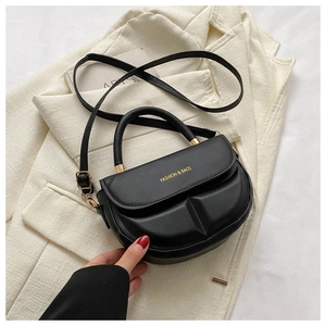 Detail of a matte black saddle bag featuring gold FASHION & BAGS lettering and gold hardware