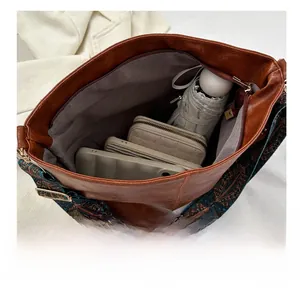 Internal view of large brown tote bag showing wide geometric strap and interior space